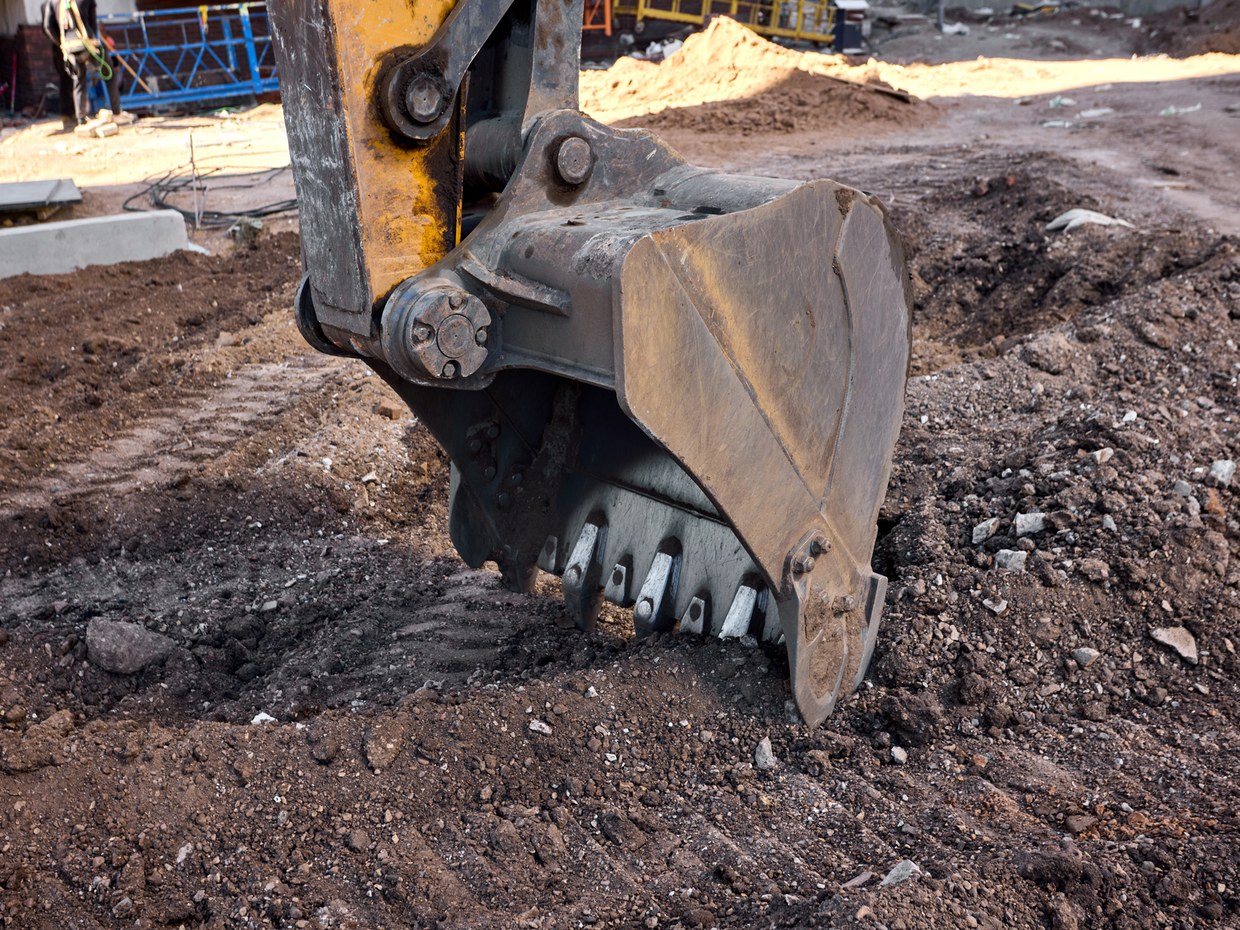 An excavator bucket cutting into contaminated ground during remediation works