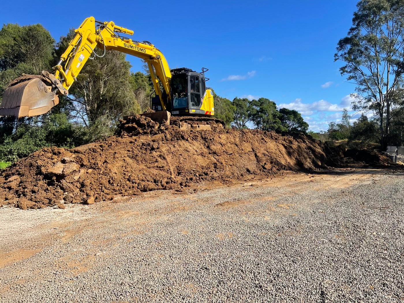 An excavator loading recovered material on a prepared site pad