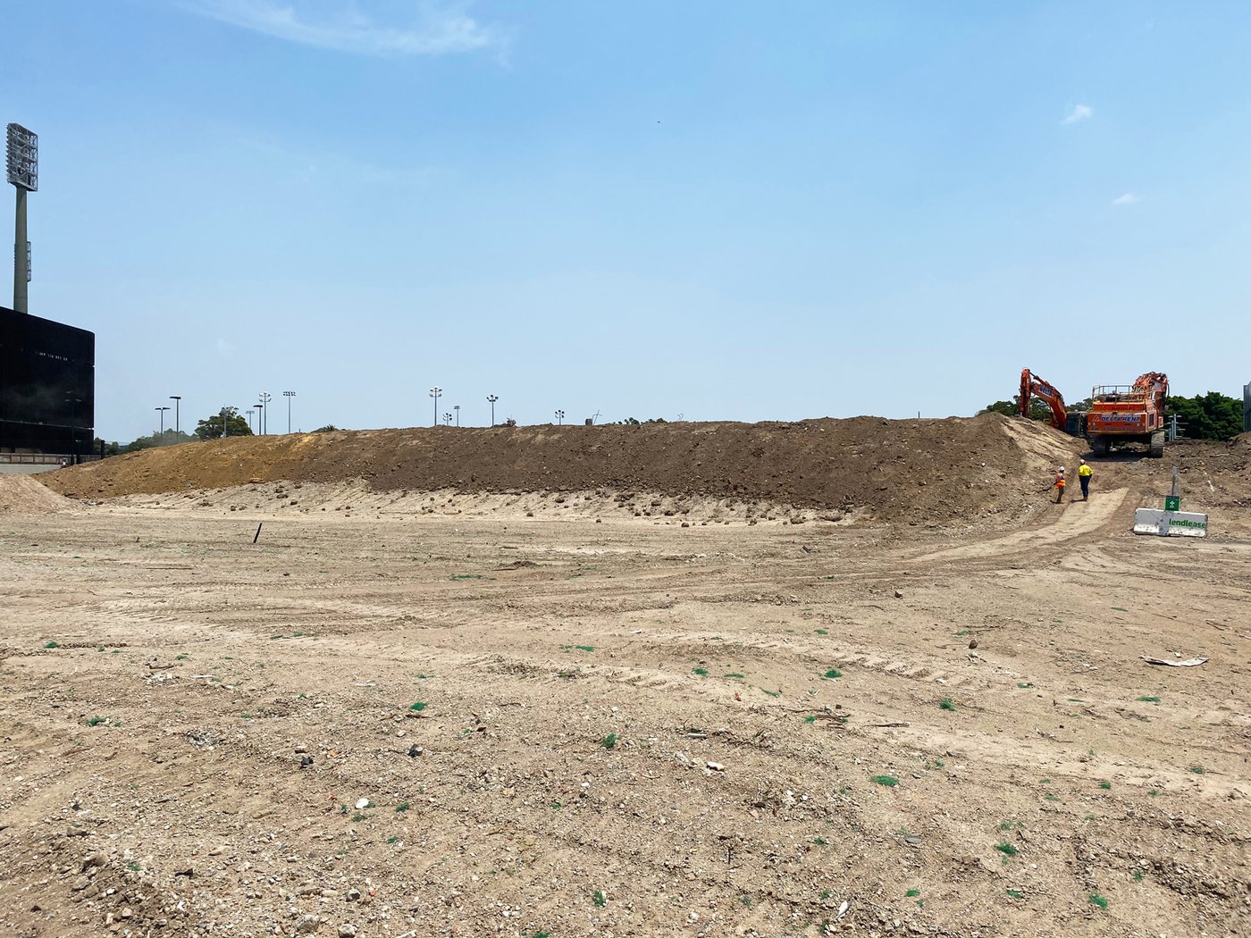 A cleared C&D processing site with a haul truck, the city skyline beyond